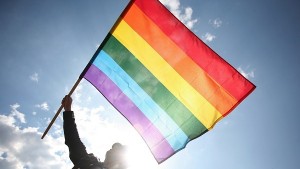 Person holding a rainbow flag during Gay Pride parade