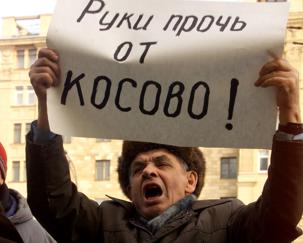 A RUSSIAN DEMONSTRATOR HOLDS A POSTER SAYING "HANDS OFF KOSOVO".