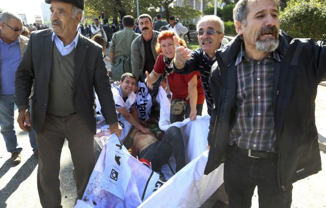 People carry a wounded person from the area of an explosion in Ankara, Turkey, Saturday, Oct. 10, 2015. Two bomb explosions apparently targeting a peace rally in Turkey's capital Ankara on Saturday has killed over 10 people, a news agency and witnesses said. The explosions occurred minutes apart near Ankara's train station as people gathered for the rally organized by the country's public sector workers' trade union. (AP Photo/DHA) TURKEY OUT