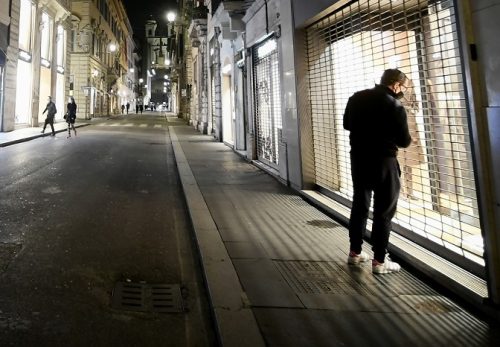 A man, wearing a face mask, looks at a closed shop near the Spanish Steps in Rome on November 1, 2020. (Photo by Filippo MONTEFORTE / AFP)